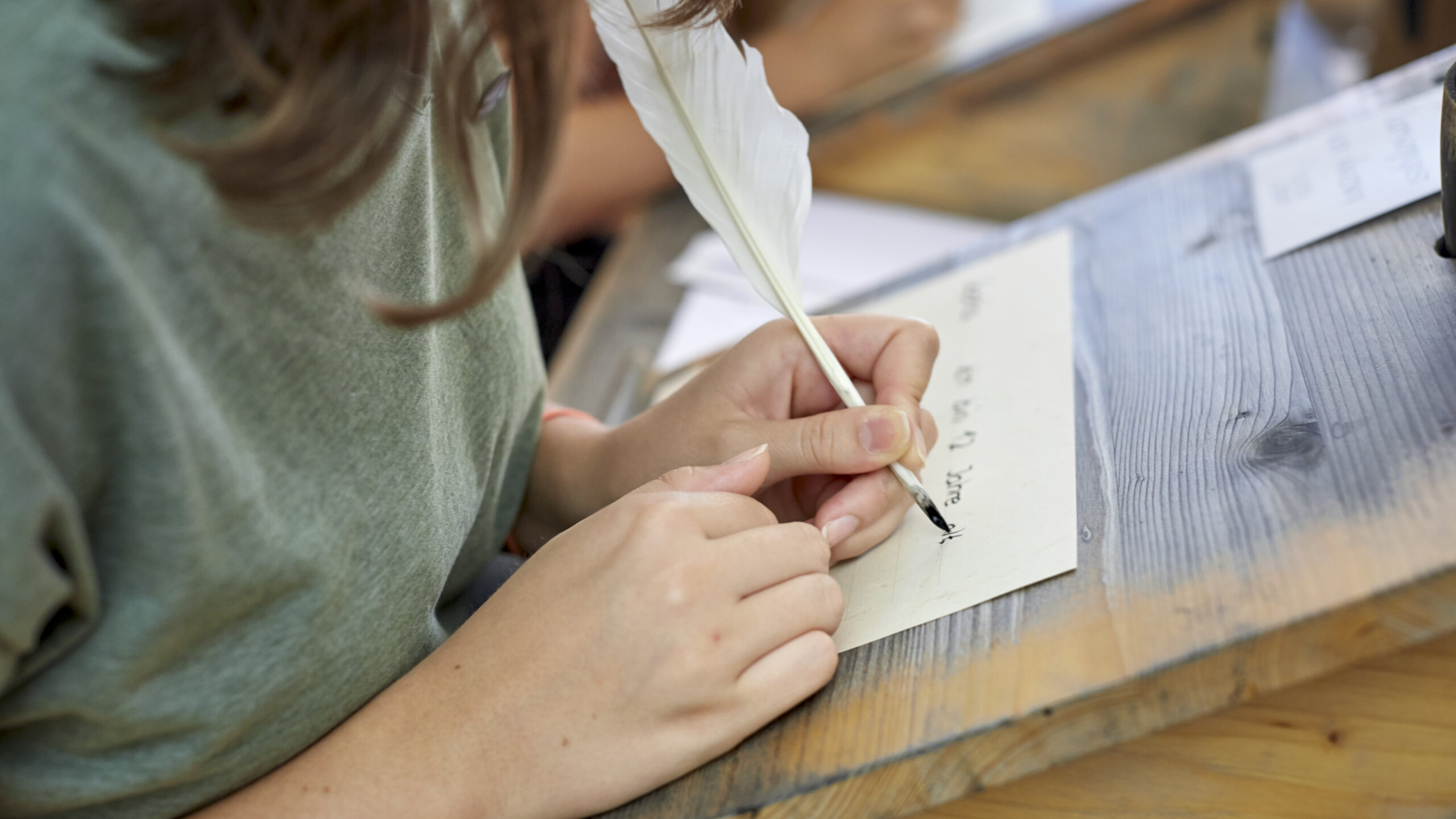 Ein Mädchen schreibt mit Federkiel und Tinte.
