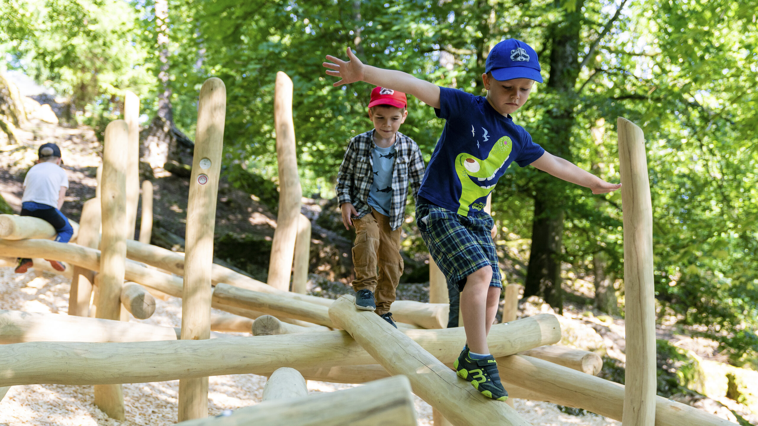 Zwei Jungen balancieren auf Holzstämmen auf dem Naturspielplatz im Natur- und Tierpark Goldau.