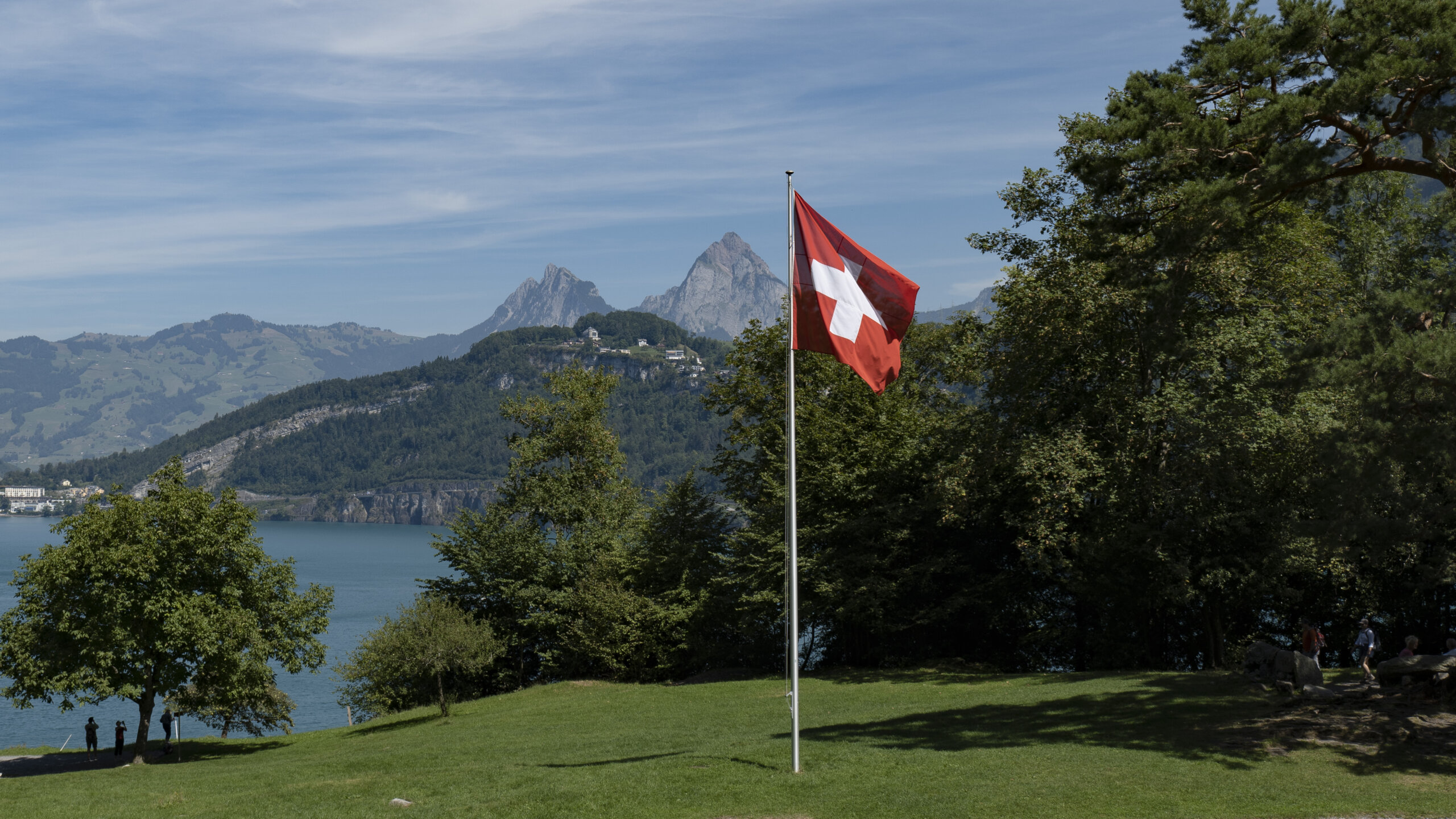 Das Rütli. In der Mitte eine Schweizer Fahne. Im Hintergrund der Urnersee, und weit weg die Mythen.
