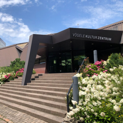 Das Vögele Kultur Zentrum von Aussen. Ein modernes Gebäude mit Blumen im Vordergrund.