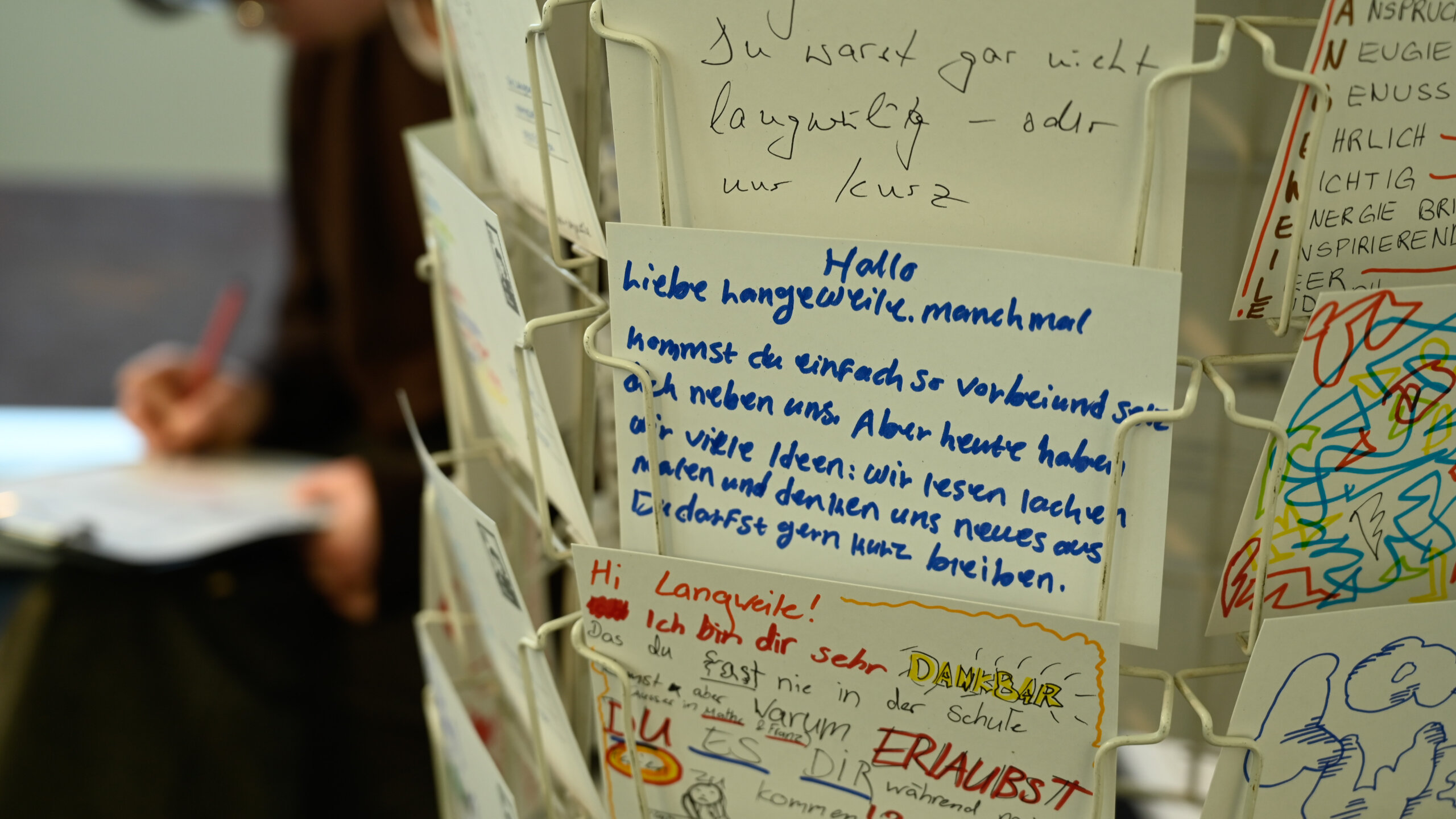 Ein Kartenständer im Vögele Kultur Zentrum. Auf den Karten haben Besuchende der Ausstellung einen Text an die Langweile geschrieben.